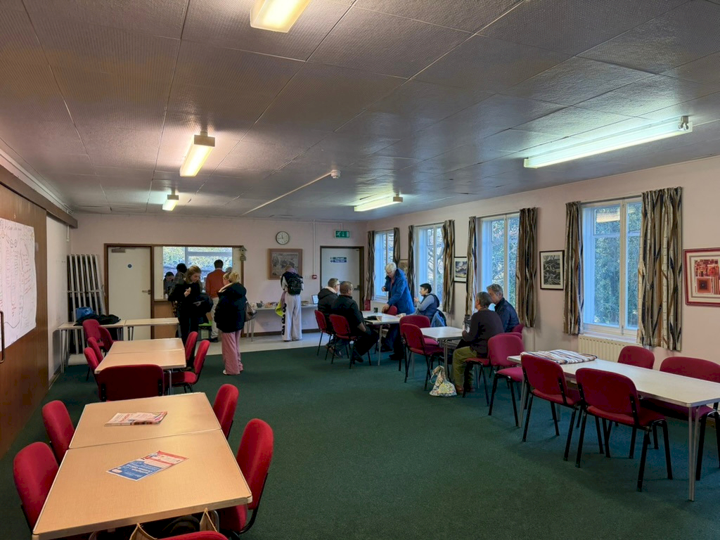 A kitchen and a meeting room with tables, and people chatting. A kitchen and a meeting room with tables, and people chatting.